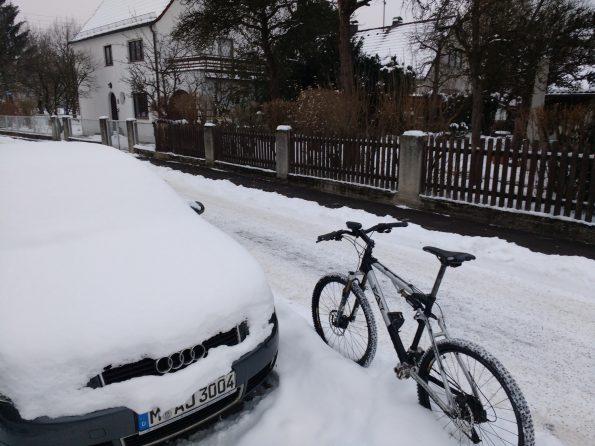 Fahrrad vor einem eingeschneitem Auto
