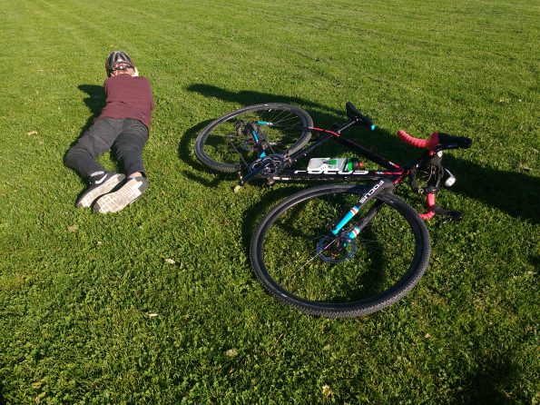 Junge und sein Fahrrad liegen auf einer Wiese in der Sonne.