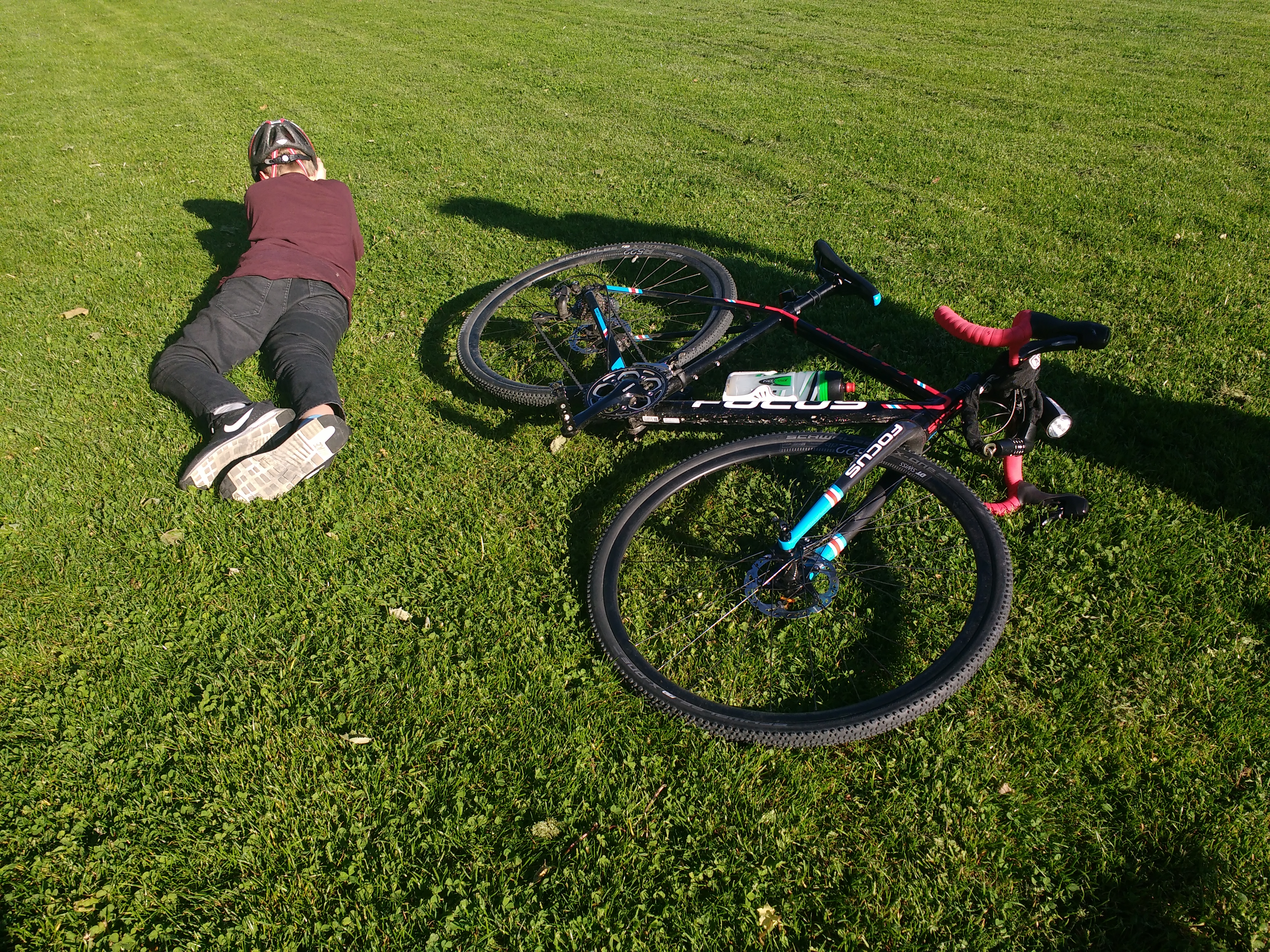 Junge und sein Fahrrad liegen auf einer Wiese in der Sonne.